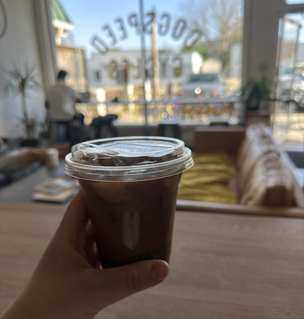 Person holding up la chingona coffee inside flat truck coffee