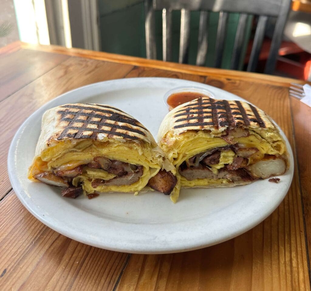 Breakfast burrito at Cenote on a plate on a brown table.