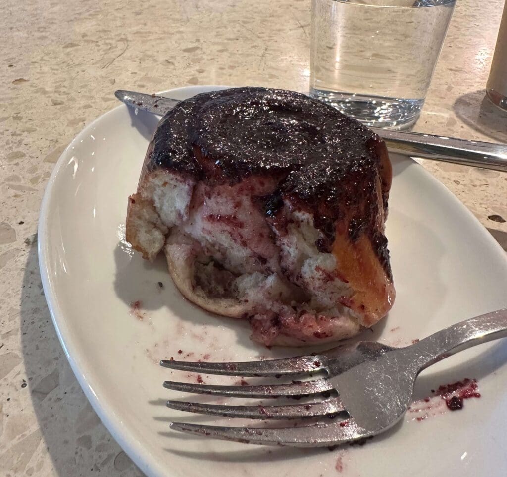 Half eaten Blueberry lemon roll on a plate with a fork from Paperboy restaurant