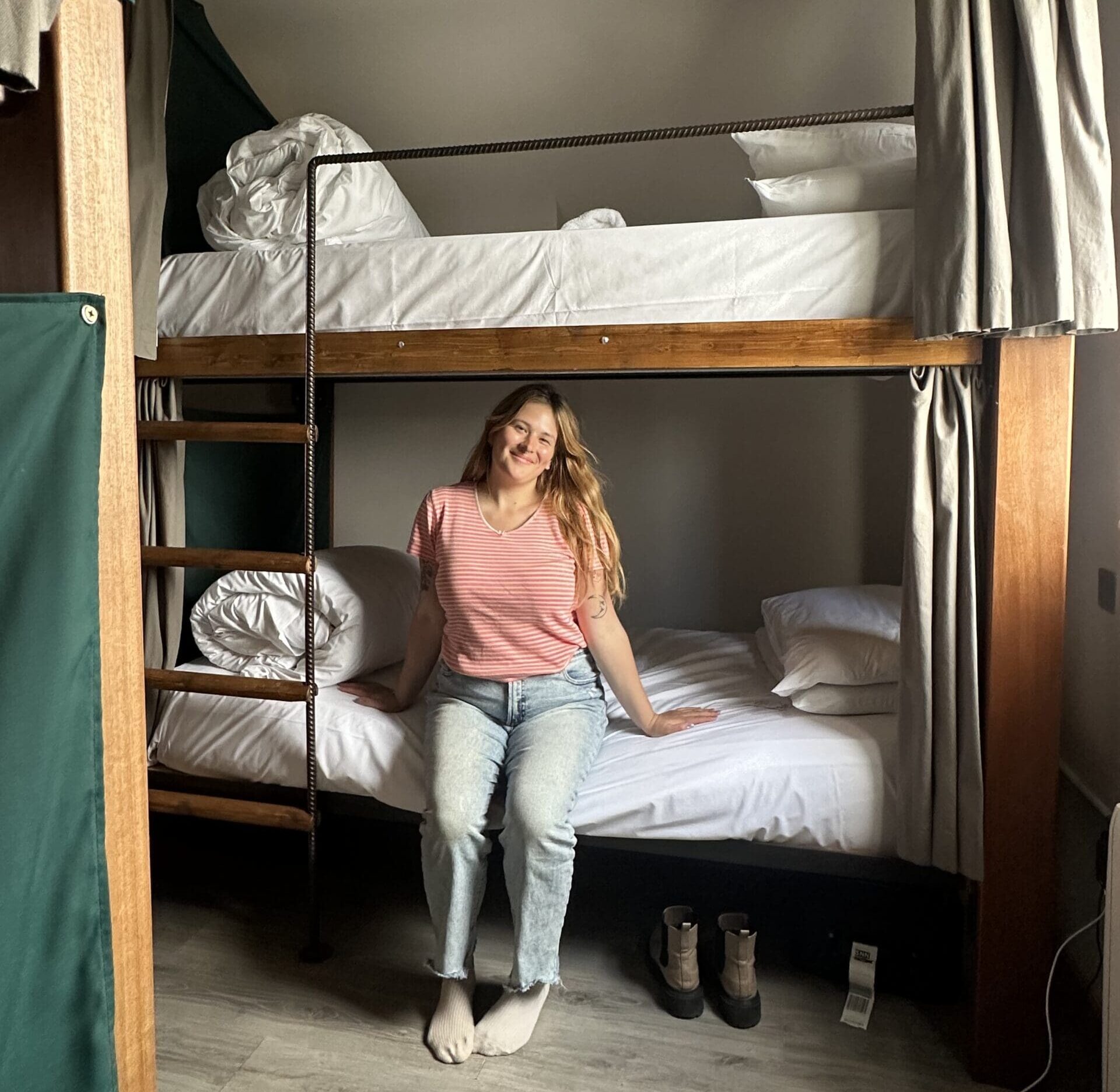 Girl sitting on bottom bunk of a hostel bed